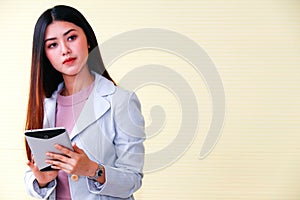 Beautiful Asian businesswoman working with laptop computer in office looking at camera photo