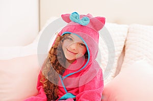 Portraiti of beautiful curly girl wearing a pink bathtowel with hood