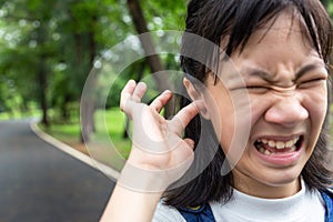 Portraits of asian little girl stressed putting a finger in to her ear,annoyed expression,insect in the ear,closeup of cute child