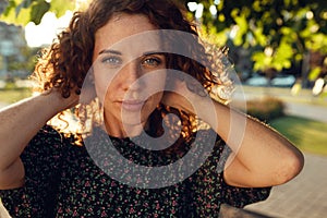 Portraits of a charming red-haired girl with freckles and a pretty face. The girl poses for the camera in the city center. She has