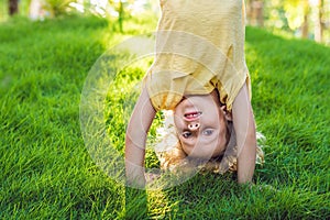 Portraits of happy kids playing upside down outdoors in summer park walking on hands