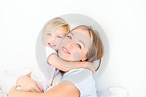 Portraits of Happy and loving mother embracing her daughter on the bed. Family morning concept. Spending free time together at hom