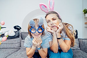 Portraits of happy smiling Caucasian mother and her son in bunny ears having fun at home on Easter day. Family sitting