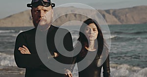 Portraits of men and women freedivers. Brutal couple in black suits against background of mountains and ocean. Beautiful