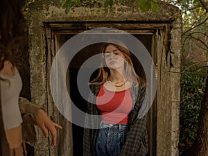 Portraits photo shoot of a model on red camisole, a jean trouser and a jacket in an abandoned house