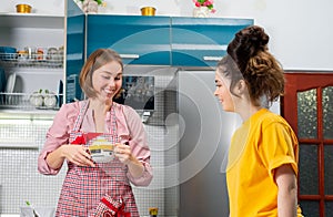 Portraits of two happy young Caucasian women cook together in the kitchen. The concept of LGBT couples and family cooking