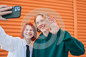 Portraits of two smiling caucasian teen friends boy and girl posing for selfie using a smartphone. Careless young teenhood . time