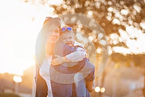 Portraits of young smiling mother and son play in an autumn park. The concept of a happy childhood