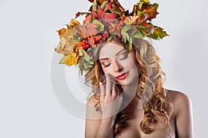 Portraiture style fashion beautiful girl with red hair fall with a wreath of colored leaves and mountain ash color bright tre