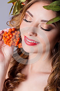 Portraiture style fashion beautiful girl with red hair fall with a wreath of colored leaves and mountain ash color bright tre