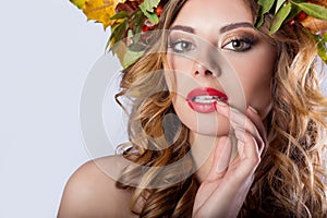 Portraiture style fashion beautiful girl with red hair fall with a wreath of colored leaves and mountain ash color bright tre