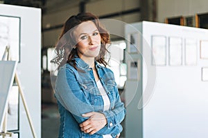 Portraiy of charming young brunette woman in jeans jacket visits the modern art gallery exhibition