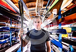 Portrat of young canoeist standing in the middle of stacked canoes. Concept of canoeing as dynamic and adventurous sport photo