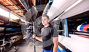 Portrat of young canoeist standing in the middle of stacked canoes. Concept of canoeing as dynamic and adventurous sport photo