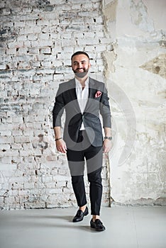 Portreit of man in black suit .on a  brick background s