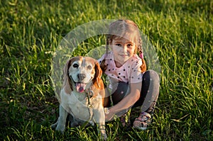 Portrert cute girl 4 years old with a dog beagle in the park on the grass in the summer