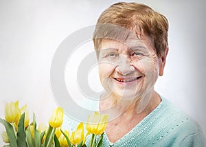 Portret of smiling, positive senior elderly woman with bunch of yellow flowers tulipan. Happy, healthy grandmother. photo