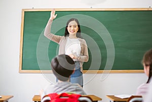 Portriat of Smiling female Asian teacher raising your hand and ask question to provide an example for students to answer in