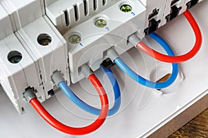 Ports of installed automatic circuit breakers connected by red and blue wires closeup