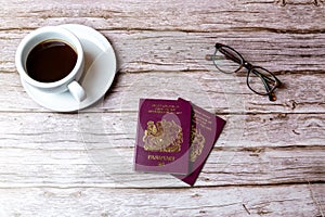 02-08-2021 Portsmouth, Hampshire, UK a pair Of British passports laid on a wooden table next to a coffee and a pair of glasses