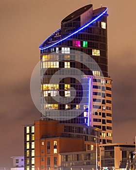 A tall modern apartment block lit up at night