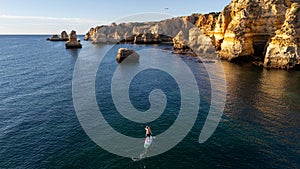 Portugal, Algarve. Cliffs, and ocean, top down aerial view of people doing paddle board sup