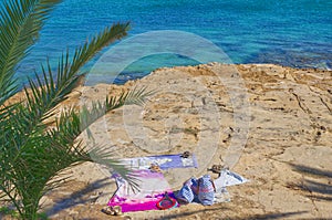 Portugal Beach towel with hat, sun glasses and flip flops on sand naturist