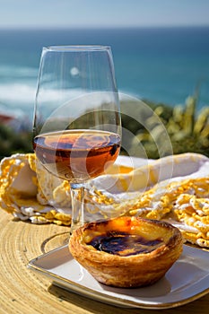 Portugal`s traditional food and drink, glass of porto wine or muscatel de setubal and sweet dessert Pastel de nata egg custard