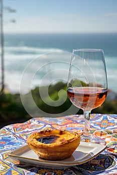 Portugal`s traditional food and drink, glass of porto wine or muscatel de setubal and sweet dessert Pastel de nata egg custard