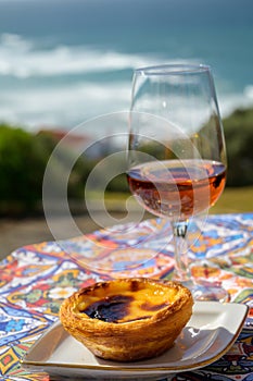 Portugal`s traditional food and drink, glass of porto wine or muscatel de setubal and sweet dessert Pastel de nata egg custard