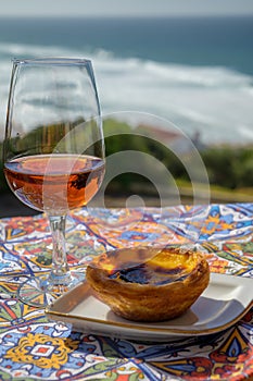 Portugal`s traditional food and drink, glass of porto wine or muscatel de setubal and sweet dessert Pastel de nata egg custard