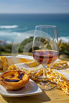 Portugal`s traditional food and drink, glass of porto wine or muscatel de setubal and sweet dessert Pastel de nata egg custard