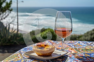 Portugal`s traditional food and drink, glass of porto wine or muscatel de setubal and sweet dessert Pastel de nata egg custard