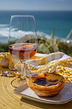 Portugal`s traditional food and drink, glass of porto wine or muscatel de setubal and sweet dessert Pastel de nata egg custard