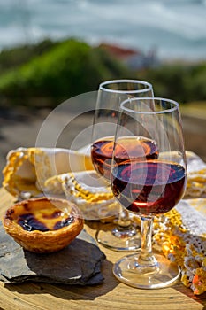Portugal`s traditional food and drink, glass of porto wine, muscatel de setubal and sweet dessert Pastel de nata egg custard tart