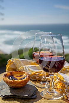 Portugal`s traditional food and drink, glass of porto wine, muscatel de setubal and sweet dessert Pastel de nata egg custard tart