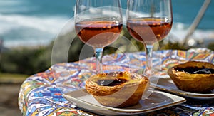 Portugal`s traditional food and drink, glasses of porto wine or muscatel de setubal and sweet dessert Pastel de nata egg custard