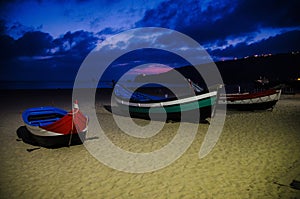 Portugal, twilight over Nazare beach, red wooden boat