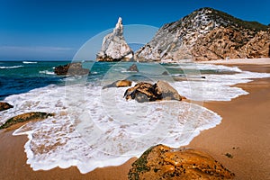Portugal Ursa Beach at atlantic ocean coast. Foamy wave at sandy beach with surreal jugged rock in coastline picturesque