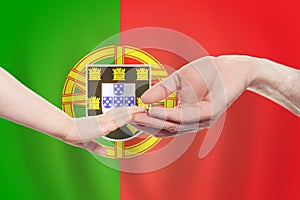 Portugese baby and parent hands on the background of flag of Portugal Help, aid, support, charity concept