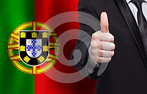 Portugese concept. Businessman showing thumb up on the background of flag of Portugal