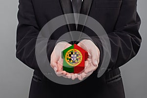 Portugese person holding wooden house with flag of Portugal Finance, investment, mortgage, loan and credit concept