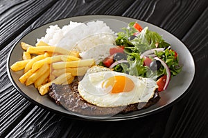 Portuguese dish Bitoque made from beef steak  topped with a fried egg served with rice and french fries, salad closeup in the