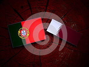 Portuguese flag with Qatari flag on a tree stump isolated