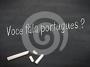 Portuguese text with the words Do you speak Portuguese? on a blackboard