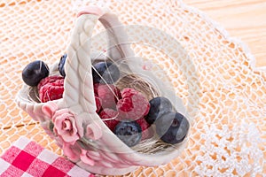 Porzelan basket with raspberry and bilberry