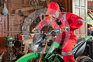 Pose of a mechanic wearing a wearpack and a hat riding a motorcycle while trying to brake a dirt bike