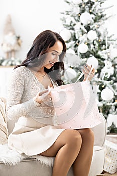 Posh dressed woman opens one of the Christmas gifts and is pleasantly surprised of what is in it