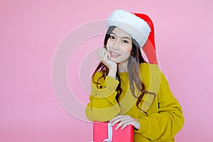 asia woman wearing long sleeve clothes on pink background with gift box in hand, Christmas or X'mas and happy new year