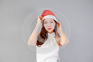 posing asian woman wearing white dress with Santa Claus red hat, holiday in festive Christmas or X'mas and happy new year concept